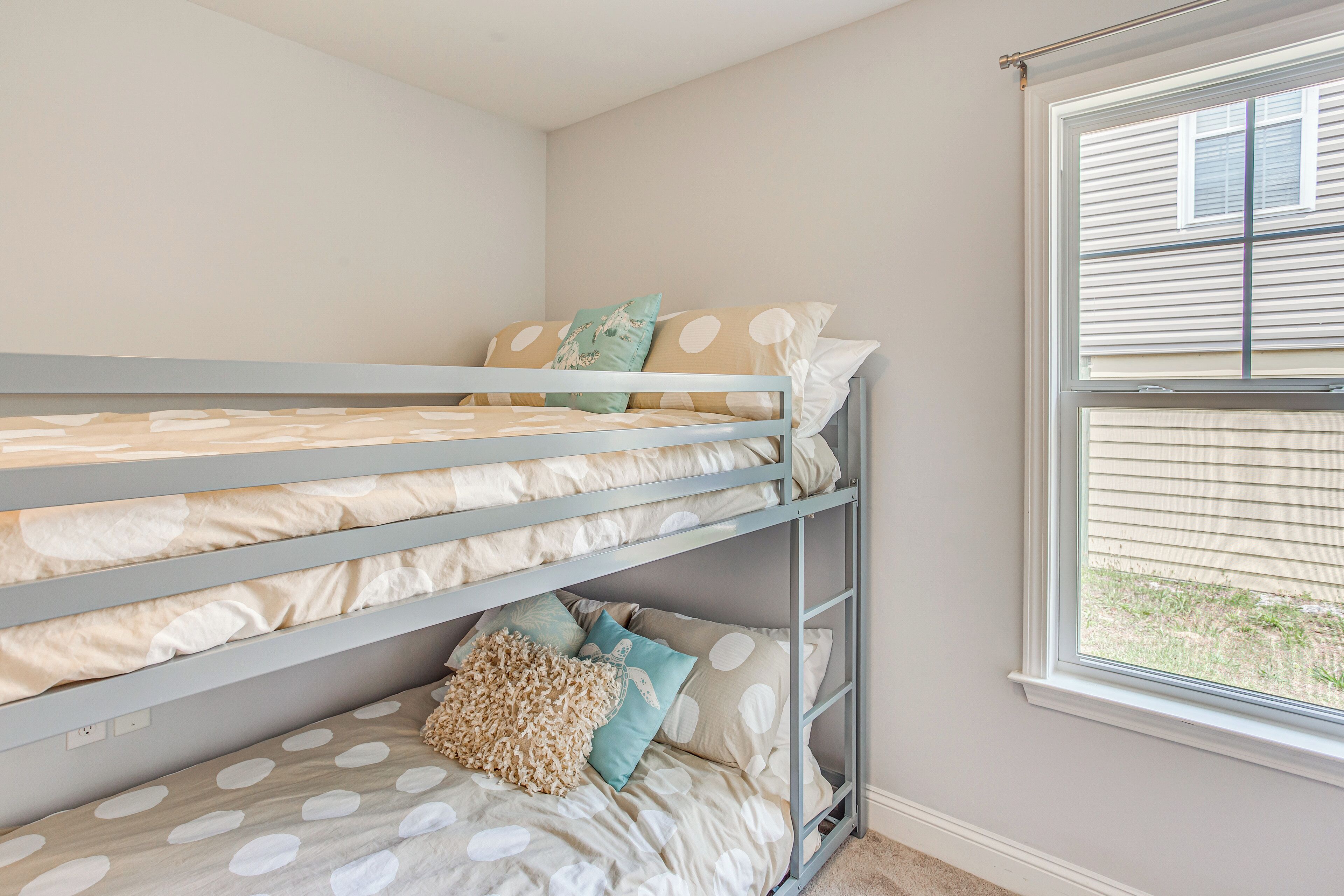 Una cama litera con ropa de cama de lunares y una ventana con persianas.