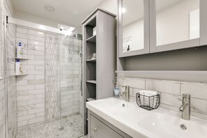 A modern bathroom with a shower, a sink, and a mirror.