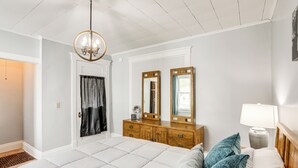 Ein Schlafzimmer mit einem großen Bett, einem Holzk dresser, zwei Spiegeln, einer Chandelieber und einer Nachttischlampe.