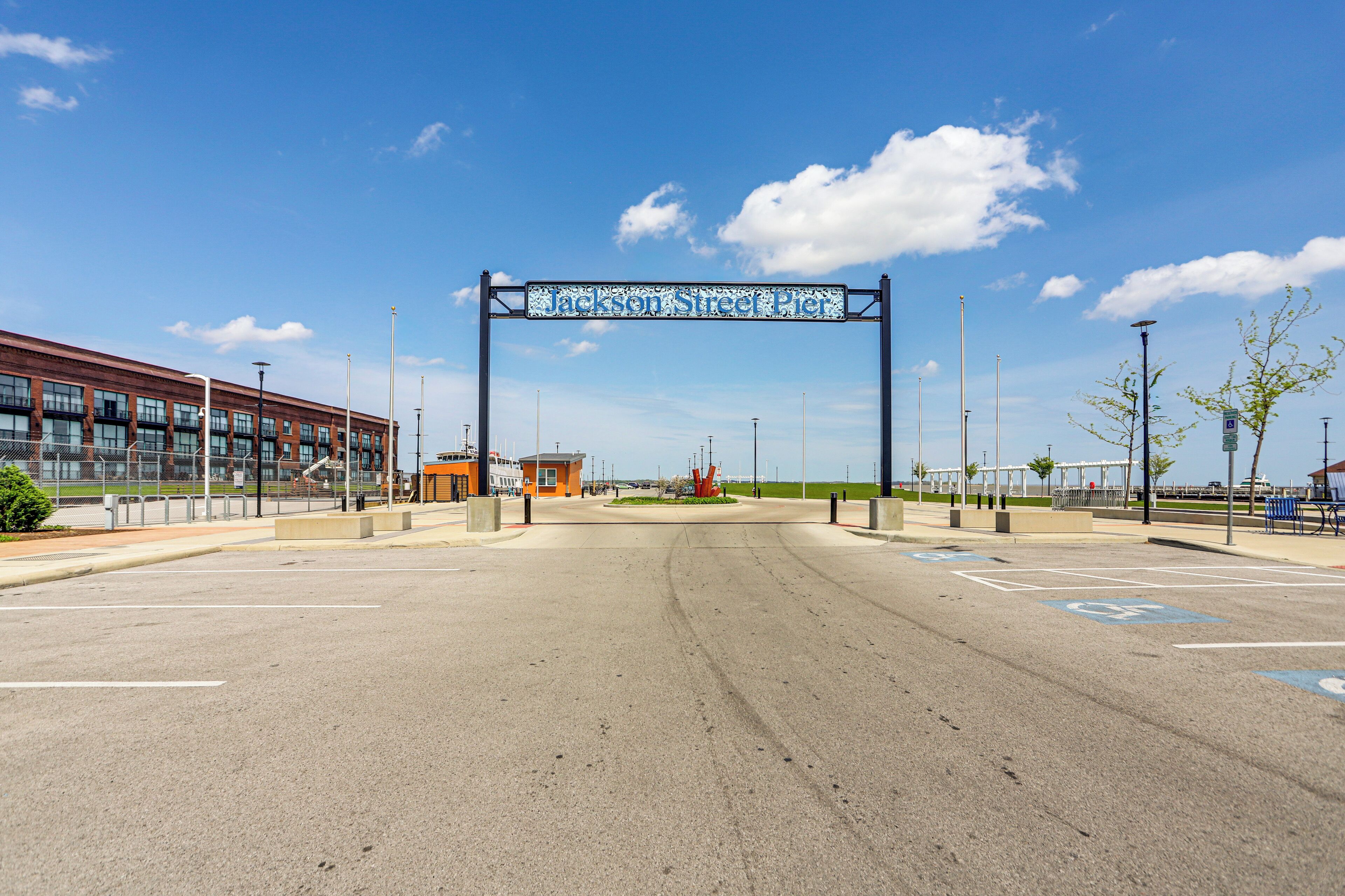 A parking lot with a clear sky, a sign reading "Jackson Street Pier", and a building with a brick facade.