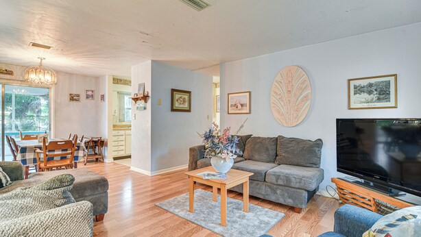 A living room with a sofa, a coffee table, a TV, and a dining area with a table and chairs.