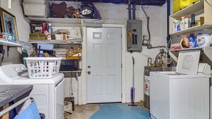 A laundry room with a washing machine, dryer, and shelves with cleaning supplies.