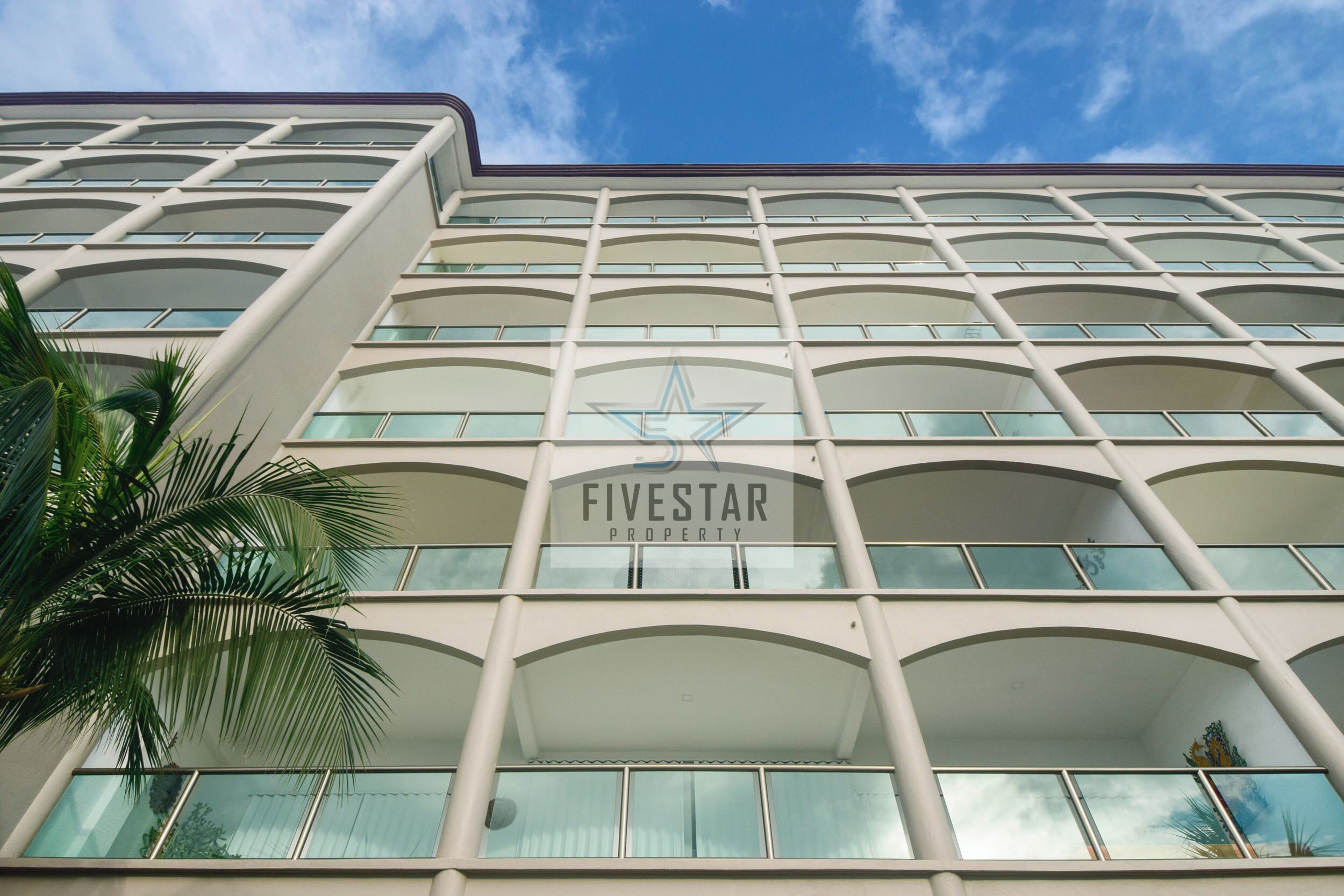 Un edificio de varios pisos con un diseño arquitectónico moderno, que presenta un logotipo destacado y el nombre 'Fivestar Property' en la fachada.
