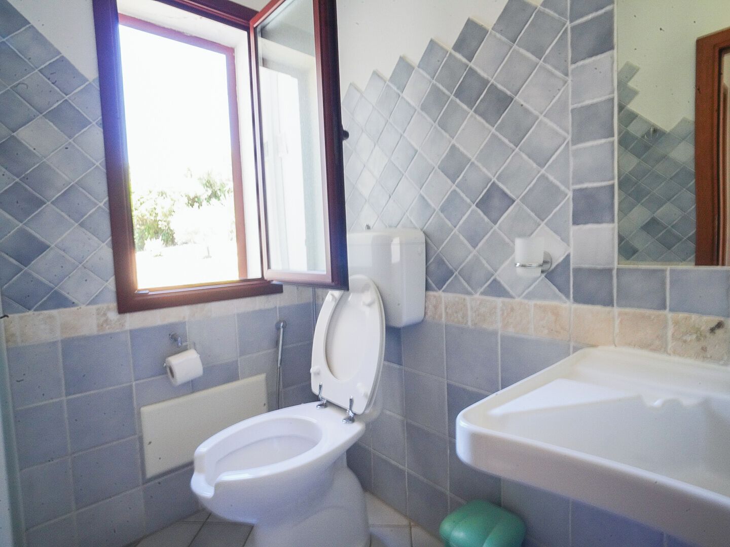 Een badkamer met toilet, wastafel en raam.