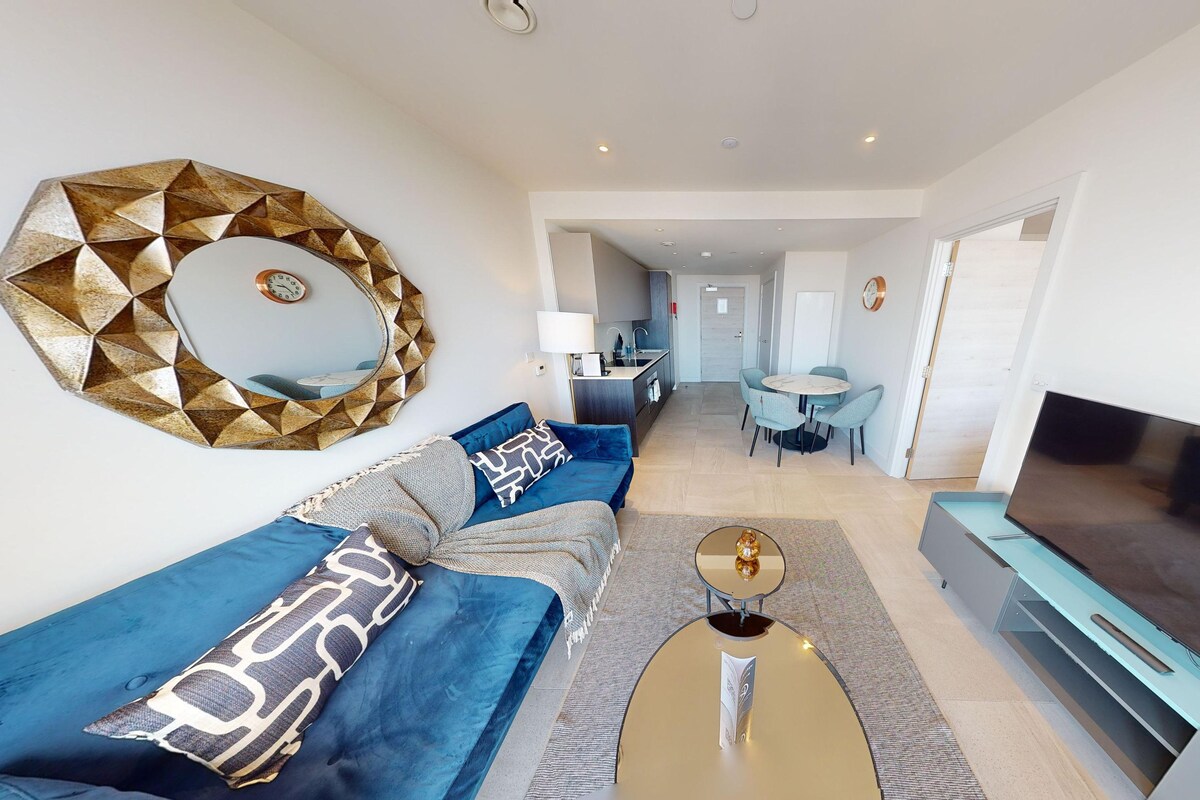 A modern living room with a sofa, TV, and a dining area with a table and chairs.