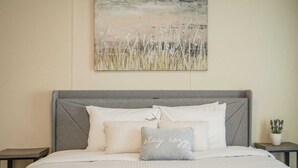 A bedroom with a bed, pillows, a nightstand, and a wall art piece.