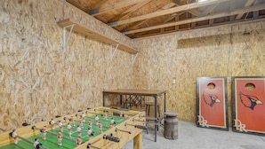 A room with a foosball table, a small table, and two cabinets with a logo.