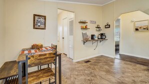 A kitchen with a dining table, chairs, a coffee station, and a door leading to another room.
