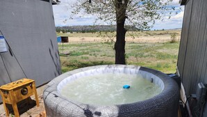A hot tub with a Coleman logo, surrounded by a wooden deck and a tree.