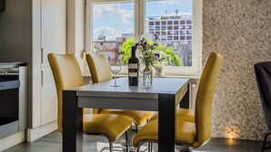 A modern kitchen with a dining table set for four, a wine bottle, and a vase with flowers. - Silver Apartment With Hot Tub And Balcony (Zagreb)