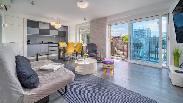 A modern living room with a sofa, a coffee table, and a dining area with yellow chairs. - Silver Apartment With Hot Tub And Balcony (Zagreb)