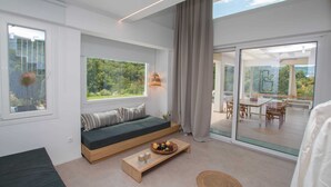 Una sala de estar moderna con un banco empotrado, una mesa de centro de madera con fruta, ventanas amplias y un puerta corrediza de vidrio que da a un área exterior.