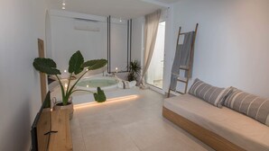 Un baño moderno con bañera, un banco de madera y una planta grande en maceta.