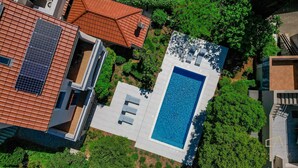 Vue aérienne d’une propriété résidentielle dotée d’une piscine, de panneaux solaires et d’une végétation luxuriante.