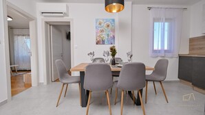Un espace repas moderne avec une table en bois, quatre chaises grises et un luminaire suspendu.