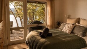 A bedroom with a bed, a window, and a view of trees and water. - Glasshouse Lake Eildon Architectural Retreat (Taylor Bay)