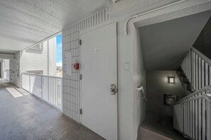 A corridor with a white door marked with the number 509, a fire alarm, and a trash bin.