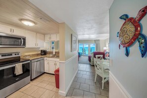 A kitchen with a microwave, stove, and dishwasher. There is a dining area with a table and chairs.