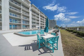 A hotel with a swimming pool, outdoor seating, and a view of the ocean.