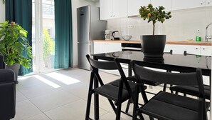 Une cuisine moderne avec des meubles blancs, un plan de travail noir et un coin repas avec des chaises noires.