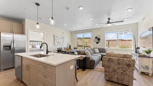 A modern kitchen with a central island, a dining area with a sofa, and a large window offering a desert view.