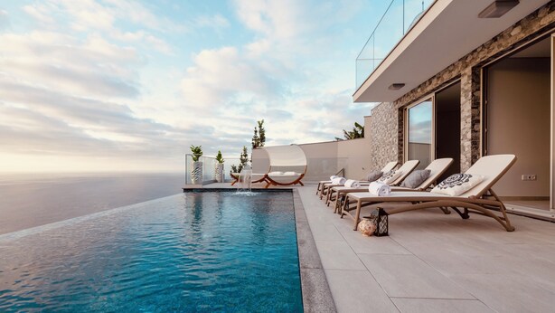 A modern infinity pool with lounge chairs and a waterfall feature, overlooking a vast ocean. - Luxury Villa Pérola (Calheta)