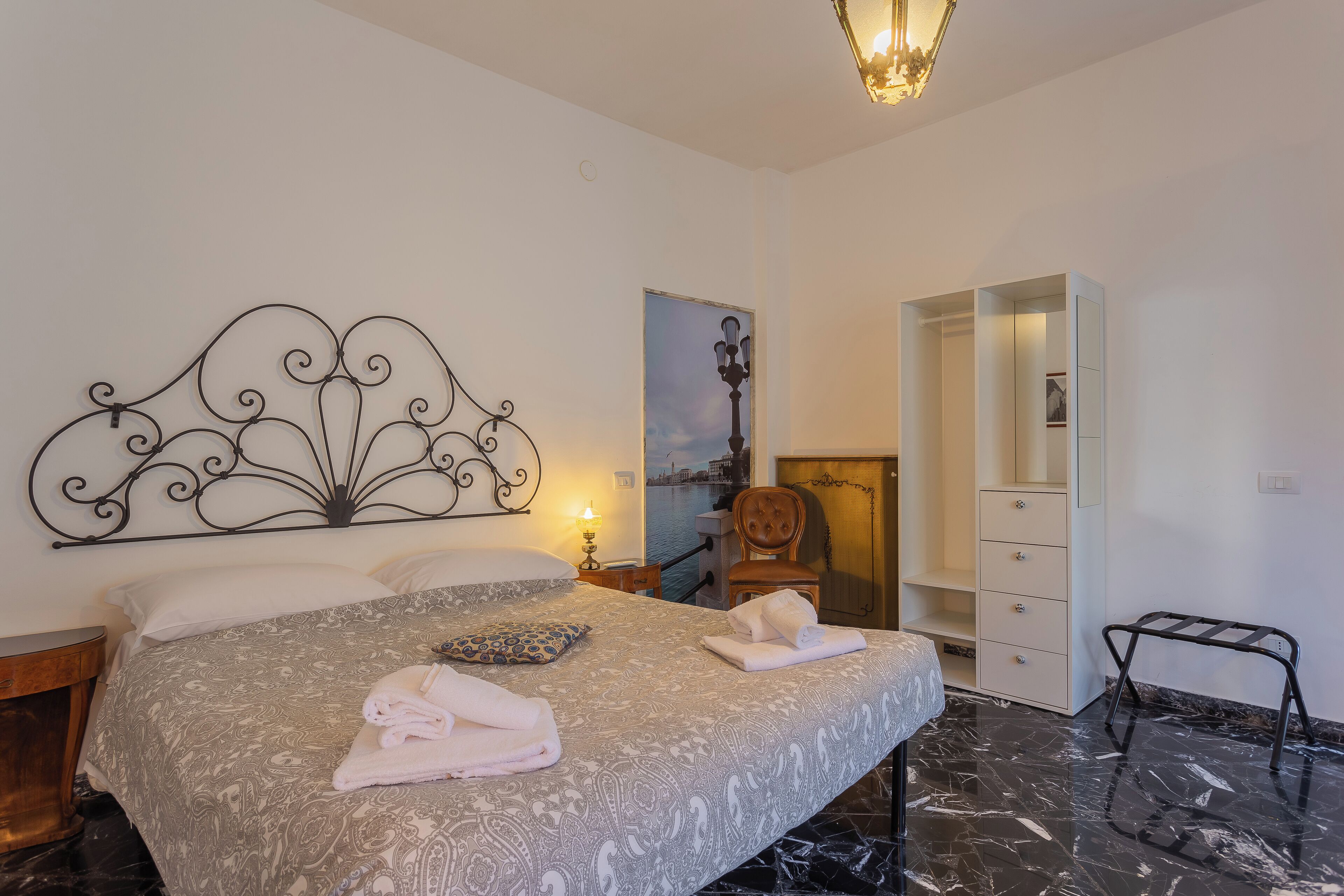 Ein Hotelzimmer mit Bett, Stuhl, Kleiderschrank und Blick auf ein Gewässer.