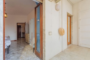 Un corridoio con un letto, un armadietto in legno e una porta con un cesto appeso al muro.