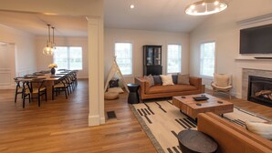 A spacious living area with a wooden dining table, sofas, and a fireplace. - New Home in Marion Village! (Marion)