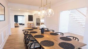 A dining area with a long wooden table, black chairs, and a vase of white flowers. - New Home in Marion Village! (Marion)