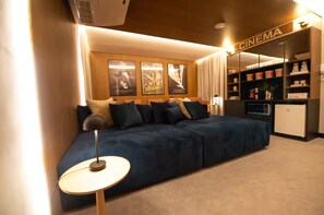 A modern living room with a sofa, a small round table, and a wall-mounted TV.