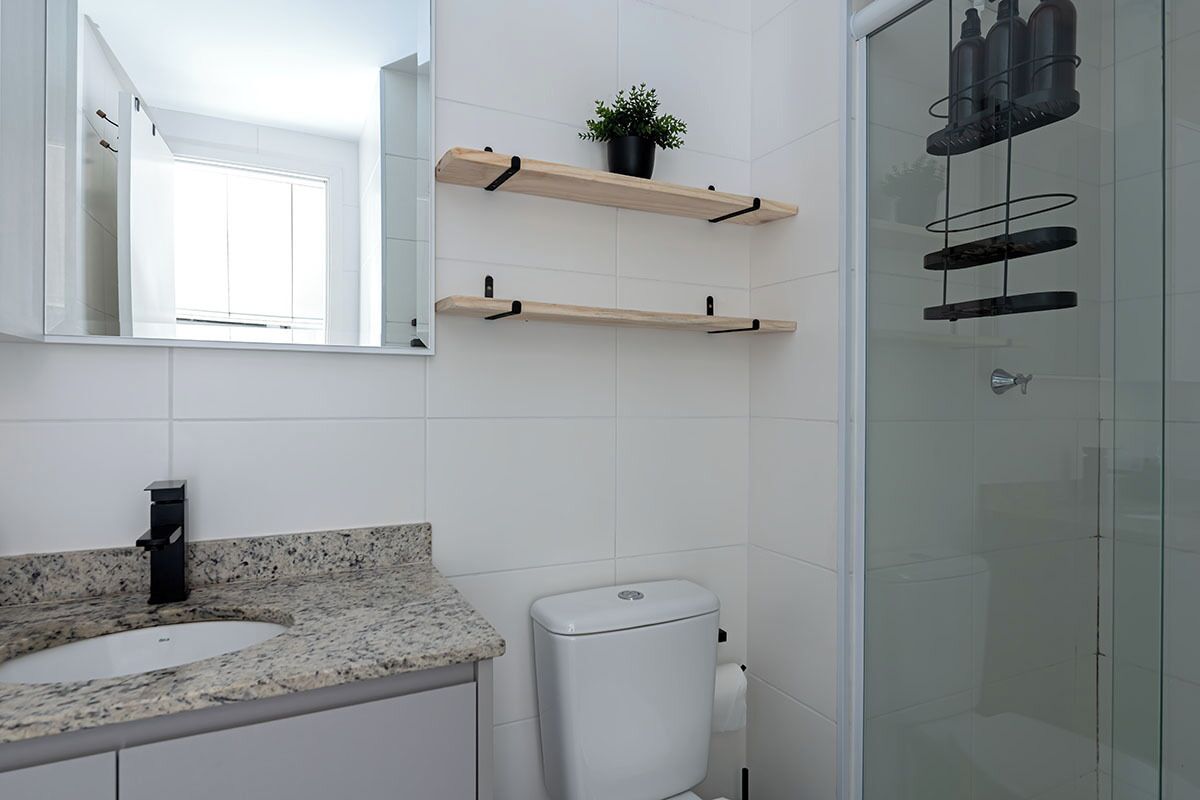 Een badkamer met een granieten aanrecht, een wit toilet en een douchecabine van glas.