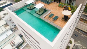 Une piscine sur le toit, avec un espace détente clos par des baies vitrées et une vue sur la ville.