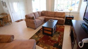 Uma sala de estar com um sofá marrom, uma mesa de centro, um rack para TV e um telefone.