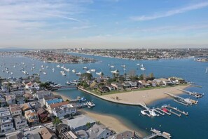 A marina with numerous boats docked, surrounded by residential buildings and a sandy beach.