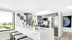 A modern kitchen with a marble island, stainless steel appliances, and a view of the outdoors.