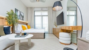 Ein modernes Hotelzimmer mit Bett, Sofa, Fernseher und Schreibtisch.