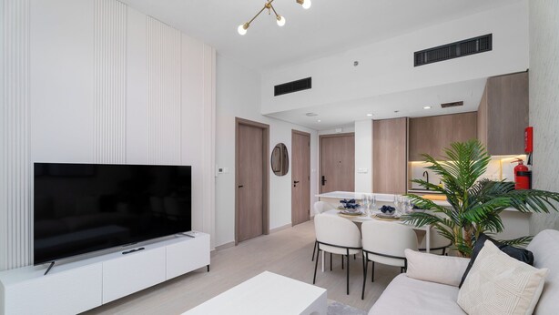 Ein modernes Wohnzimmer mit Flachbildfernseher, einem weißen Couchtisch und einem beige gefärbten Sofa.