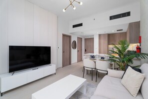 A modern living room with a flat-screen TV, a white coffee table, and a beige sofa. - Nasma Holiday Homes - Laya Heights (Dubai)
