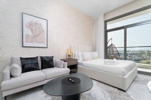 Een moderne hotelkamer met een groot raam, een bank, een bed en een salontafel.