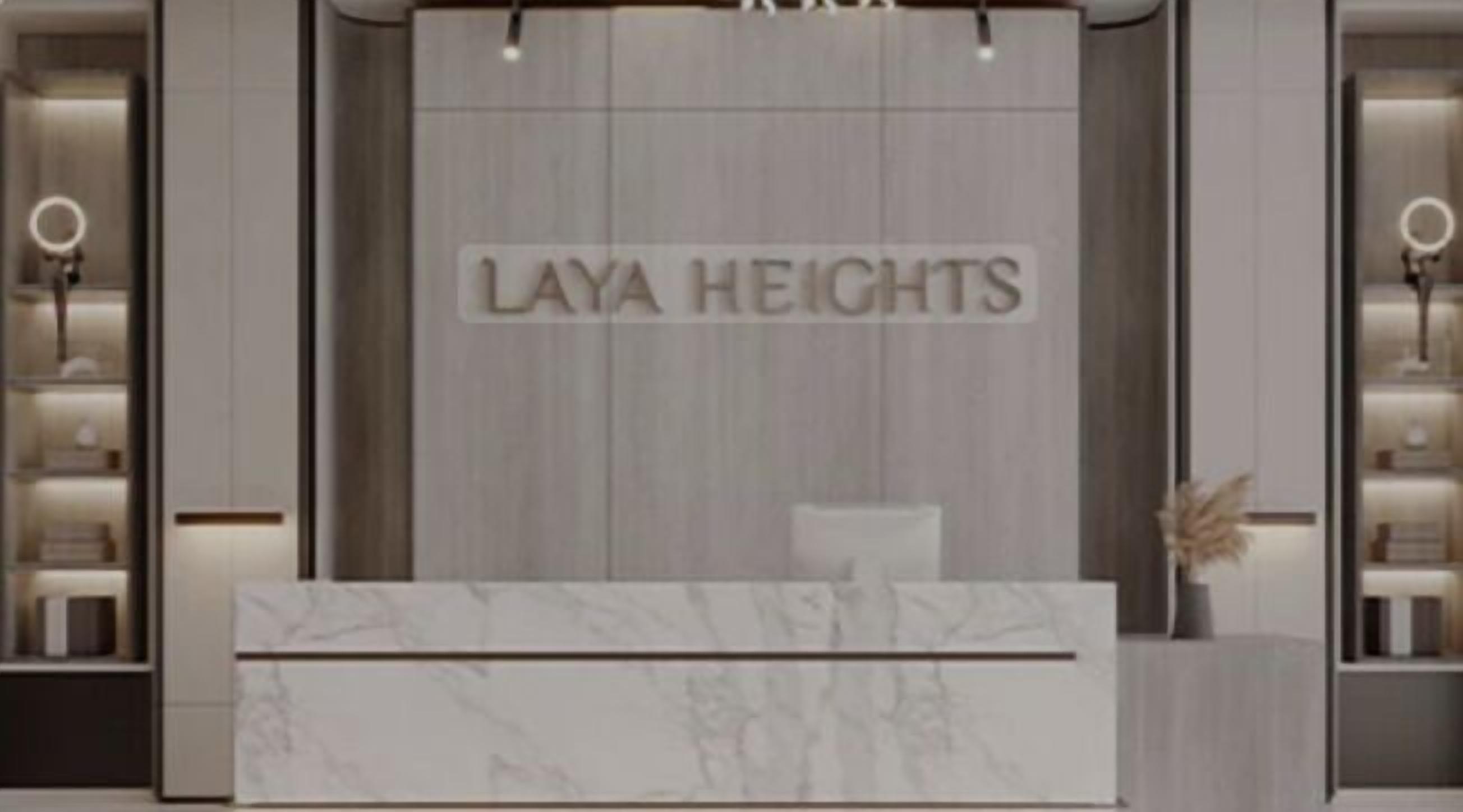 Un comptoir d’accueil avec un plateau en marbre et une enseigne indiquant « Laya Heights ».