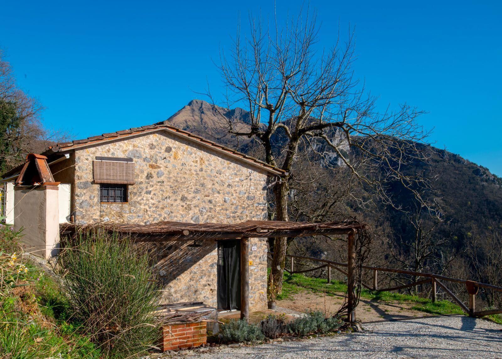 Un bâtiment en pierre avec un toit en pente, une clôture en bois et une montagne en arrière-plan.