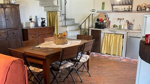 Una cocina rústica con una mesa de madera, sillas y suelo de ladrillo.