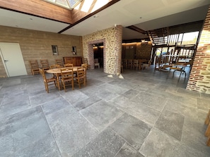 A spacious indoor area with a high ceiling, stone pillars, and a mix of wooden and stone flooring.