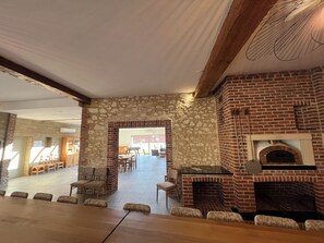 A spacious indoor area with a stone wall, a brick fireplace, and a glass table.