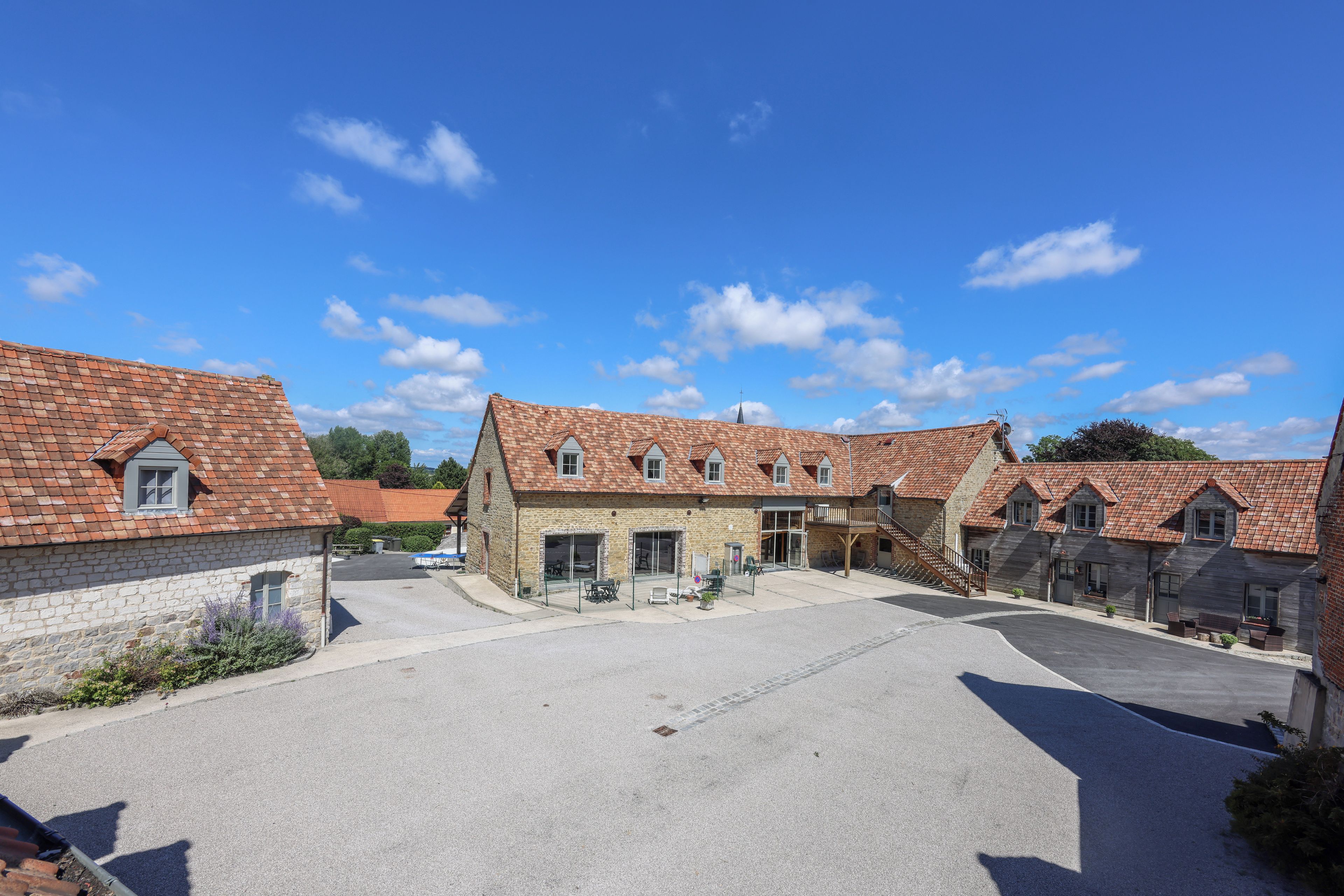 A courtyard with stone buildings, a covered seating area, and a clear sky.
