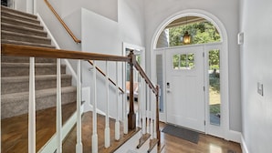 A staircase with wooden handrails and carpeted steps leading to a white door with glass panels. - Spacious 5 Bedroom, Hot Tub, Arcade Room, EV Charger, Handicap & Quiet Culdesac! (Raleigh)