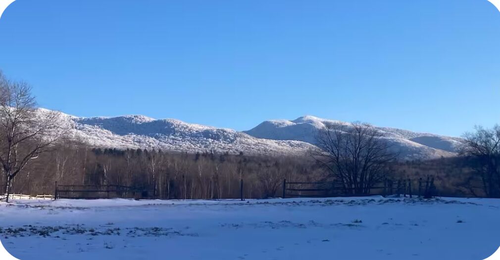 A snowy landscape with mountains in the background and a clear blue sky.