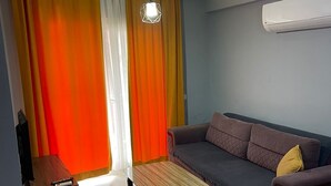 Una sala de estar con sofá, mesa de centro, mueble para televisión y ventilador de techo.