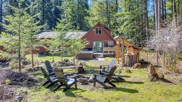 A cabin with a deck, surrounded by a forest. - Cabin at the Forest Edge | Hot tub, pet friendly (Packwood)
